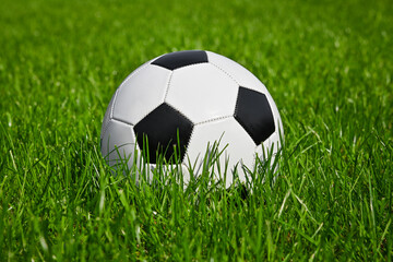 Fototapeta na wymiar Football ball in green grass of soccer field