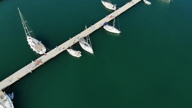 Flying over the seaport in clear sunny weather. View from above on a large number of yachts and ships. Beautiful clear green Turkish Sea in the port.