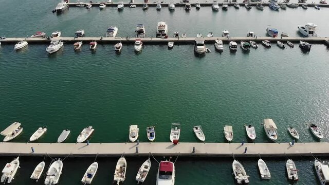 Flying over the seaport in clear sunny weather. View from above on a large number of yachts and ships. Beautiful clear green Turkish Sea in the port.