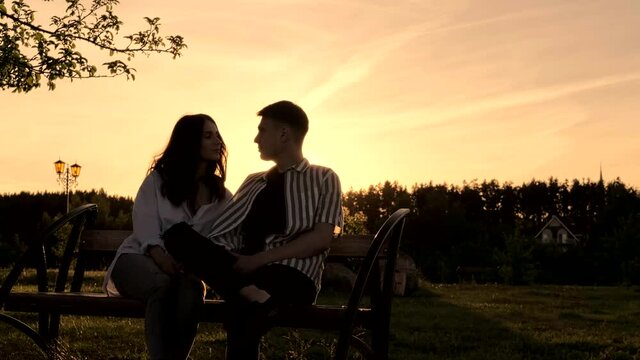Lovely couple have a cute conversation while sitting on a bench under