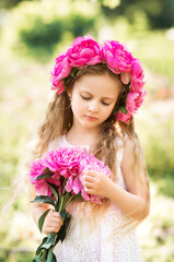 Naklejka premium Portrait of a girl with pink flowers. A wreath of peonies on the child's head.