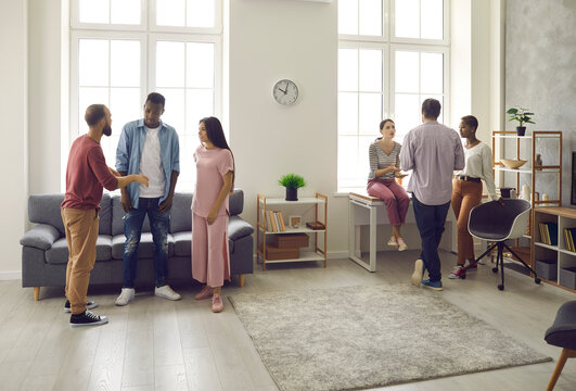 Caucasian and African American women and men communicate with each other at home. Friends split into two small groups playing a game during a party at home or discussing something interesting.