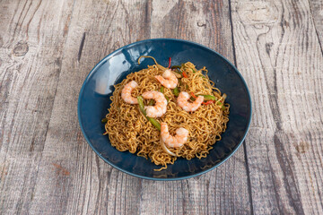 Sauteed noodles with vegetables and prawns with yakisoba sauce on a blue plate