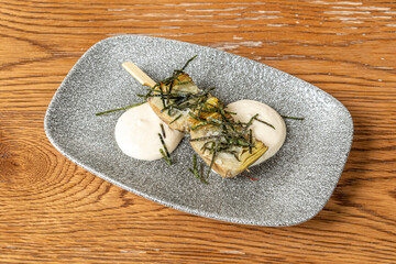 gray tray with a skewer of candied artichokes and shredded dried seaweed on top