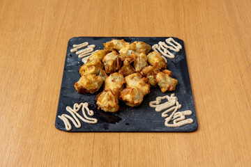 Artichoke hearts battered and fried in olive oil with sauce to accompany and black slate plate