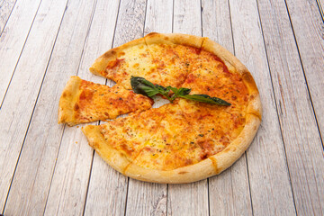 Super margherita pizza sliced into portions ready to eat for breakfast, snack or dinner on white wooden table