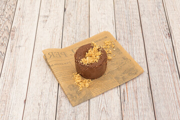 One serving chocolate cake with biscuit sand on top on a light wooden table