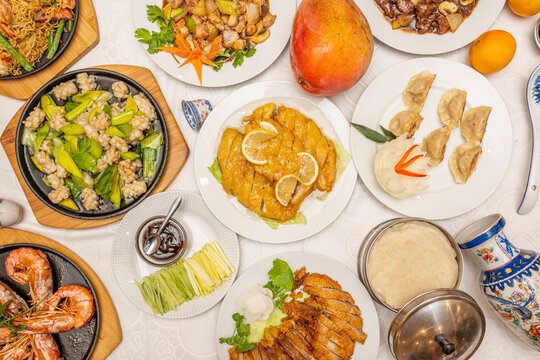 Top view image of Chinese food dishes. Lemon Chicken, Pekin Duck, Chinese Rice Pasta, Stuffed Gyozas, Mango and Grilled Shrimp