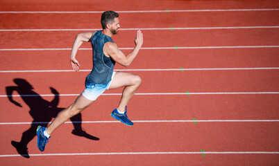 Obraz premium energetic athletic muscular man runner running on racetrack at outdoor stadium, hurry up