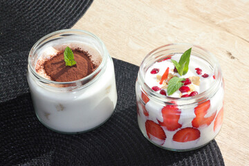 Desserts in cups are on the table in a patisserie. Strawberry and cream. Mint leaves. Cozy place. A sweet break. Tiramisu, magnolia.