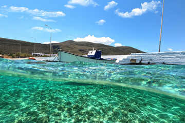 Sea level and underwater split photo of traditional wooden fishing boat anchored in Aegean island...