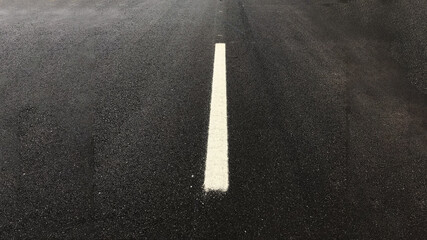 Asphalt texture background with a white intermittent strip of high-quality paint, black road smooth...