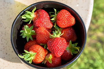 Fresh strawberries in a black plate on a granite table