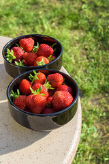 Fresh strawberries in a black plate on a granite table