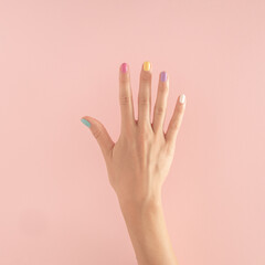 women hands with colorful nails on the pastel pink background. copy space.  summer modern tropical abstract art with female hand. minimal background idea with number five