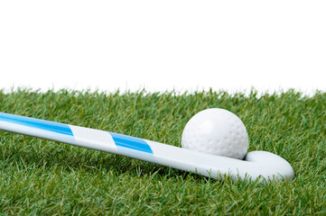 Field hockey stick and ball on the green field. Professional sport concept