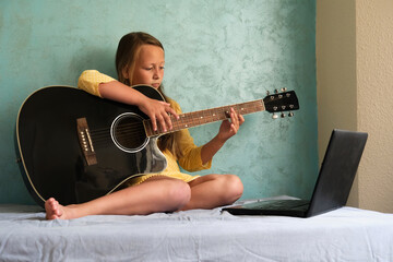 a little girl is learning to play the guitar