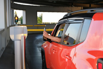 The man in the car, inserts the ticket into the machine in the parking lot. Payment, entering the parking lot or leaving the garage © Andrii