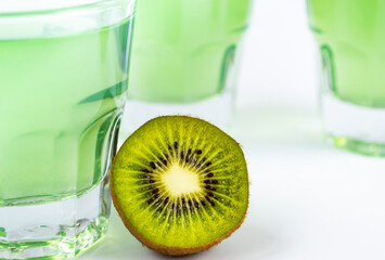 Sweet dessert, kiwi jelly in glass glasses and next to fresh kiwi, cut into two halves on a white background