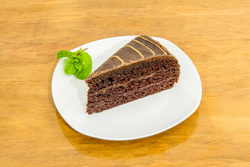 Portion of delicious chocolate cake with three layers of sponge cake with shiny chocolate coating