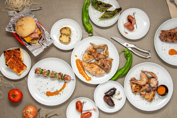set of dishes made in a restaurant with a charcoal grill. Roasted sausages, chicken and vegetable skewers, charcoal chicken, barbecue wings, roasted peppers