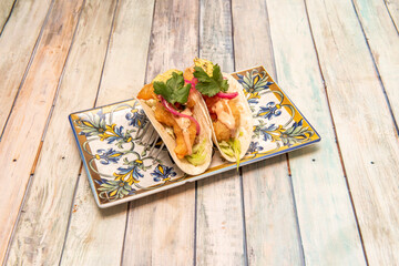 tacos with crunchy tortillas stuffed with seafood battered with iceberg lettuce and parsley on wooden table