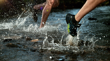 Close-up of man feet running in water, freeze motion.