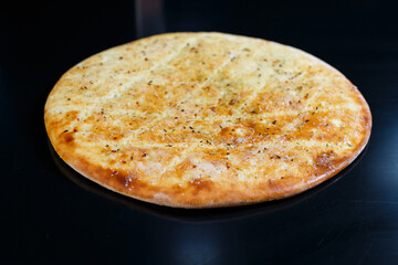 Sliced pizza on a black stone background, top view. Freshly baked focaccia with cheese