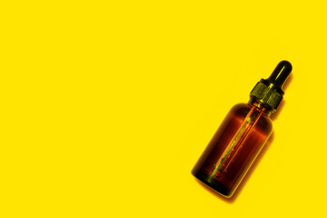 Brown bottle with essential oil on yellow background