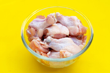Fresh raw chicken wings (wingstick) in glass bowl on yellow background.