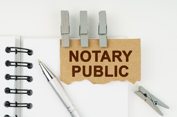 On a white background lies a notebook, a pen, clothespins and cardboard with the inscription - Notary Public