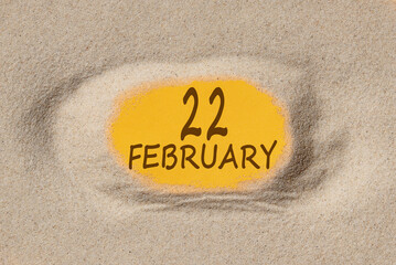 February 22. 22th day of the month, calendar date. Hole in sand. Yellow background is visible through hole. Winter month, day of the year concept