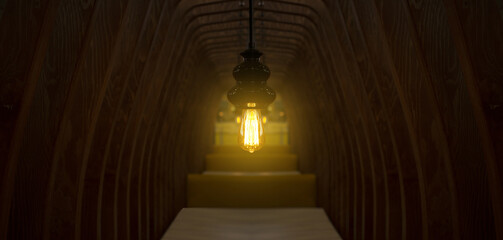 A yellow beautiful delicate lamp hangs in a cozy cafe restaurant in a wooden tunnel for love, it burns with a beautiful light, a place where delicious food, a coffee shop