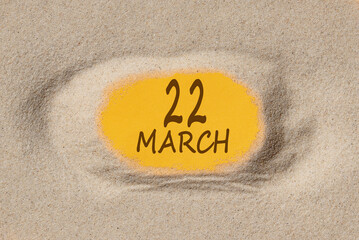 March 22. 22th day of the month, calendar date. Hole in sand. Yellow background is visible through hole. Spring month, day of the year concept