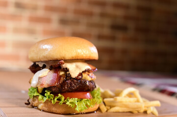 hamburger sandwich with open brioche bread cream cheese fries bacon sauces on the table on blurred background
