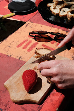 Close-Up of a woman slicing a block of foie gras on a chopping board and a strawberry