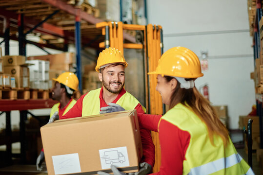 Positive warehouse workers carrying heavy box