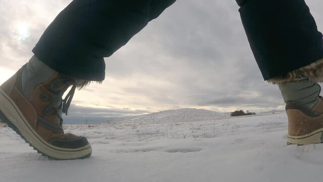 Close u of womans boots walking on the snowy mountain road in the winter day