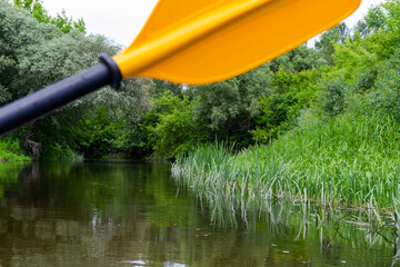 Paddle for yellow rowing on the water while kayaking on the river, in the background of nature