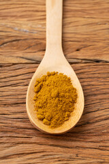 Closeup of turmeric in a spoon over wooden table