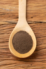 Closeup of ground black pepper on a spoon over wooden table