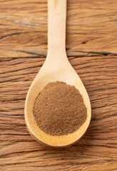 Closeup of ground cumin on a spoon over wooden table