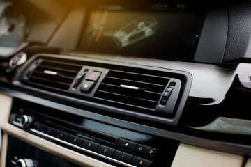 Close up Air Vent in modern car. Ventilation vents with air flow deflectors and car emergency lights button and display.