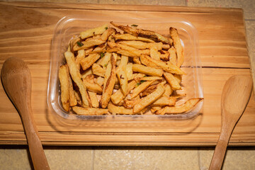 Golden classic fries make an incredible appetizer in a plastic tray for distribution as a side dish or to eat alone. Mediterranean cuisine photography for magazine or online delivery menu concept.