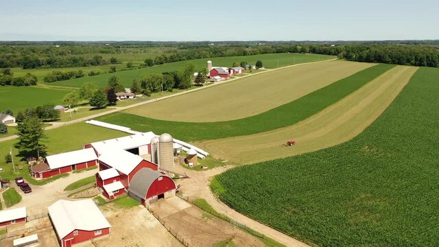 Countryside summer landscape. Farms, agricultural fields, tractor working in field. Birds eye view of Midwest USA. Daytime, sunny