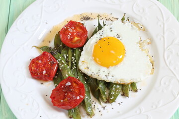 Scrambled eggs with green beans, tomatoes with white wine on a green, wooden background