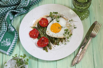 Scrambled eggs with green beans, tomatoes with white wine on a green, wooden background