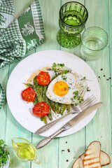 Scrambled eggs with green beans, tomatoes with white wine on a green, wooden background