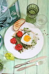 Scrambled eggs with green beans, tomatoes with white wine on a green, wooden background