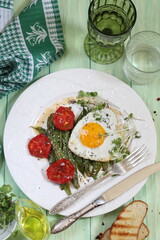 Scrambled eggs with green beans, tomatoes with white wine on a green, wooden background